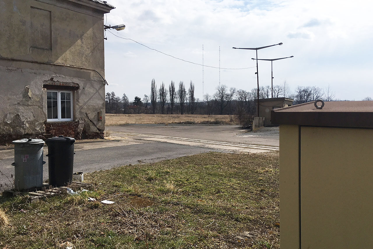 Záblesk koleje mezi pozůstalými budovami pivovaru. V pozadí slavné liblické vysílače. Nedalsko odsud se nacházela ústřední část cukrovaru.