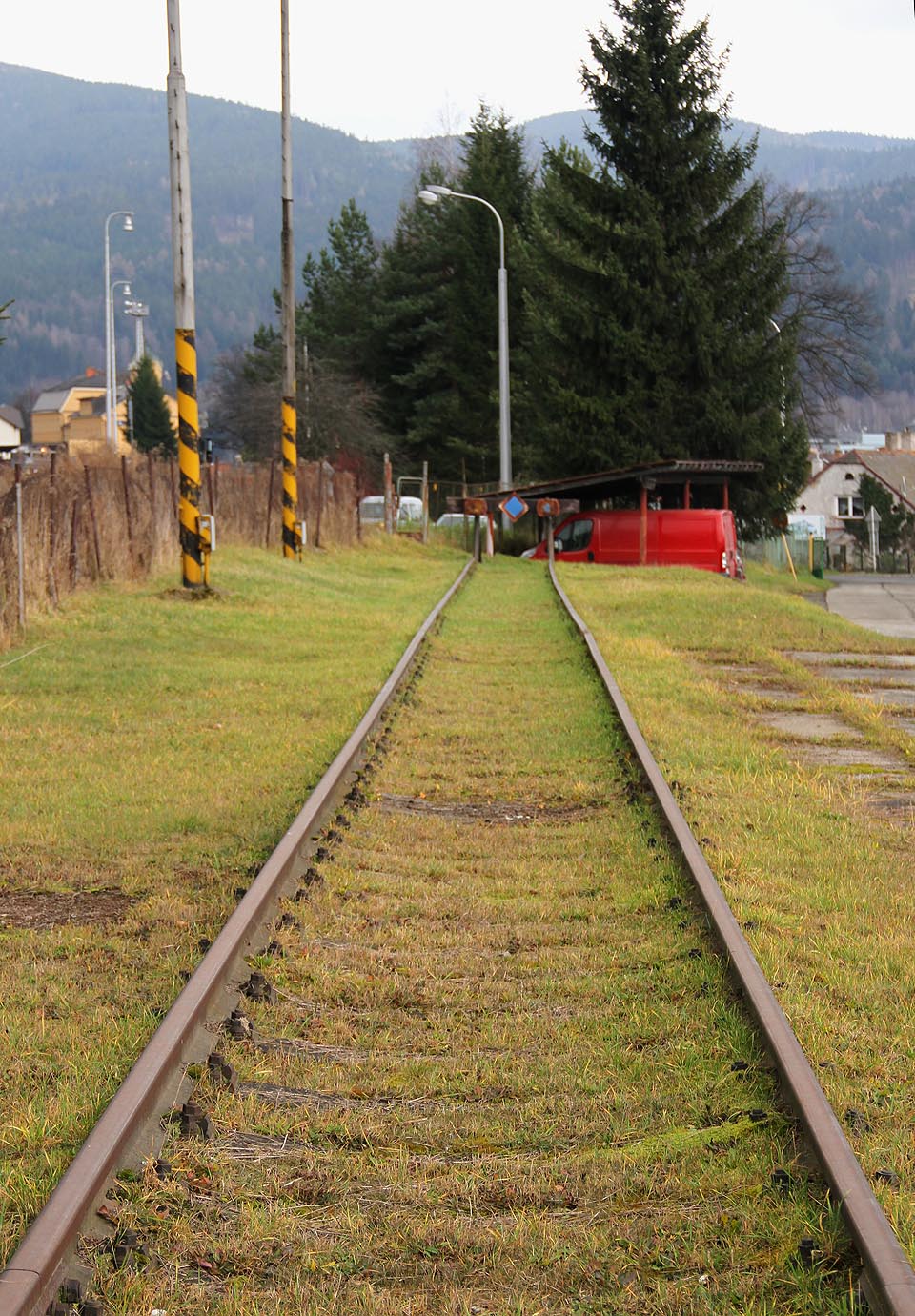 Odvratná kolej se vrací zpět do oploceného areálu strojírny.