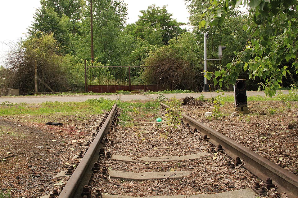 Oslepené posunové návěstidlo se už ani nepokouší bránit ve vjezdu do zarostlého areálu litoměřických mrazíren. Na kolej odpojenou od zbytku železniční sítě v Evropě a Asii už stejně žádný vlak nevjede.