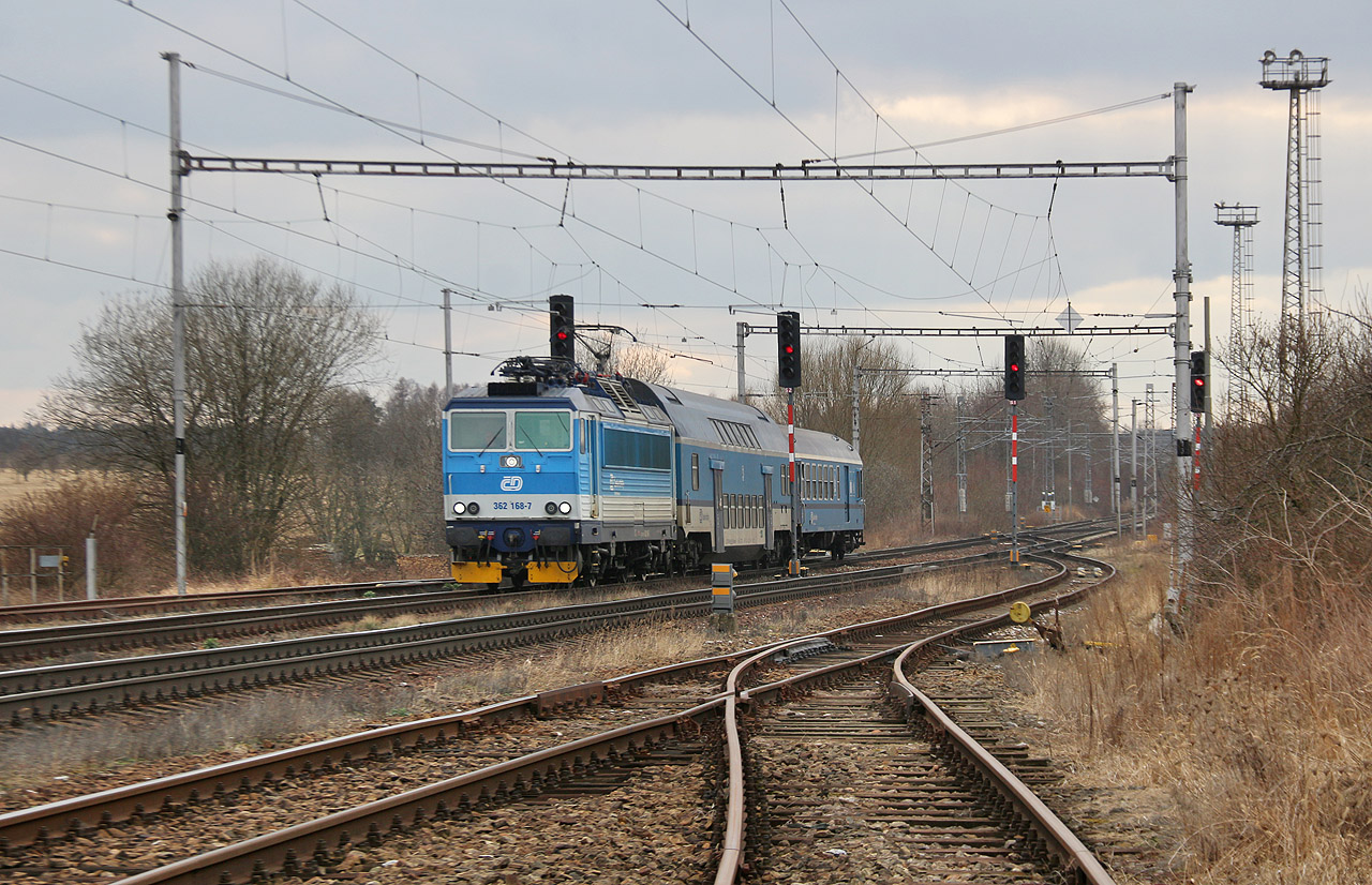 O osm minut zpožděný vlak Os5912 ze Žďáru nad Sázavou do Kolína přijíždí v šedivém nedělním odpoledni dne 27. února 2022 na dopravní kolej č. 2a stanice Vlkaneč. Po vystoupení dvou a nastoupení jedné cestující se mezi strojvedoucím a vlakvedoucím strhne krátká rozepře o tom, jak má správně vypadat pohyb ruky při návěsti č. 238 Souhlas k odjezdu, díky které vlak zvýší zpoždění na 9 minut. Posléze se konečně ozve zabzučení tyristorových měničů na lokomotivě 362 168-7 a vlak se vydá na svou další pouť z Vysočiny do Středočeského kraje.