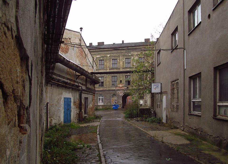 Původní cesta procházející branou paláce se stáčí k severu a končí mezi výrobními halami.