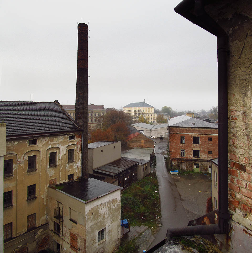 Pohled na Vlněnu z jednoho z mnoha střešních zákoutí. Tady plyne čas jiným tempem a ruch ulic zdola sem doléhá jen napůl.
