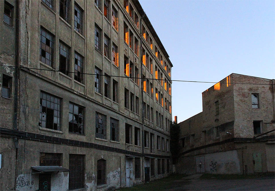 Zapadající slunce prosvěcuje slepé okenní rámy v nejmladším jihozápadním cípu areálu brněnské Vlněny.