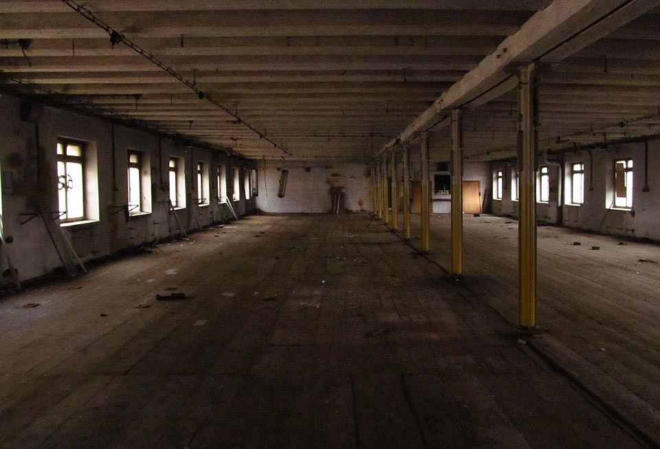 Druhá nejstarší budova v areálu Vlněny přiléhá z jihu k třípatrovému Bochnerovu paláci. Stejně vysoká jako on, nabízela čtyři patra nízkých hal s dřevěnými stropy nesenými litinovými sloupy. Tady hučely stroje dávno před koncem 19. století.