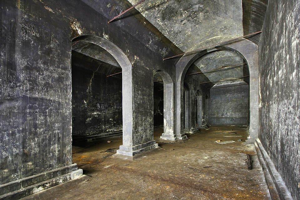 Černá omítka pokrývá pětici cihelných oblouků i klenby stažené litinovými pásy.