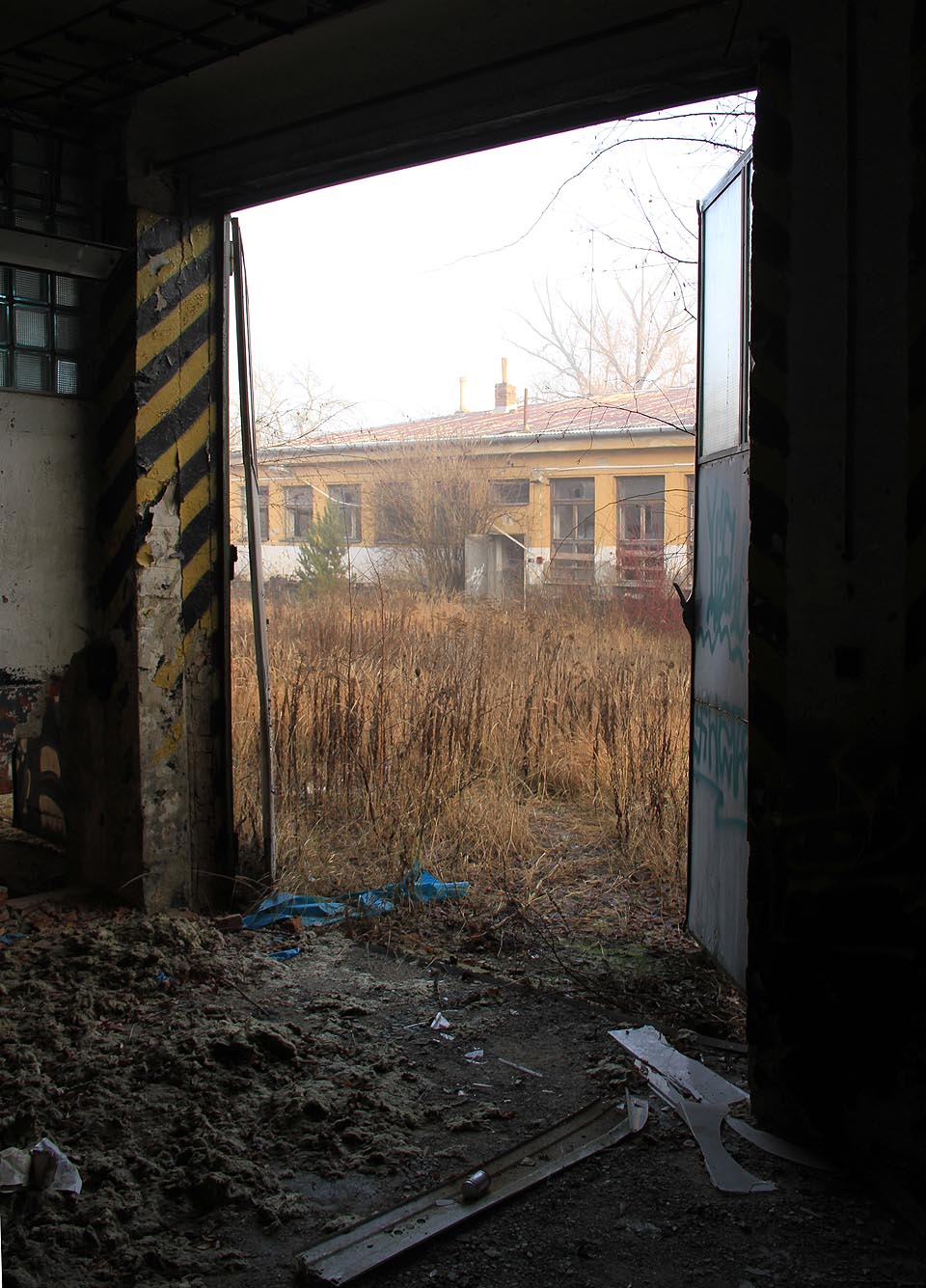 Pohled otevřenými vraty z budovy 1 na budovu 2. Tady se zastavil čas.