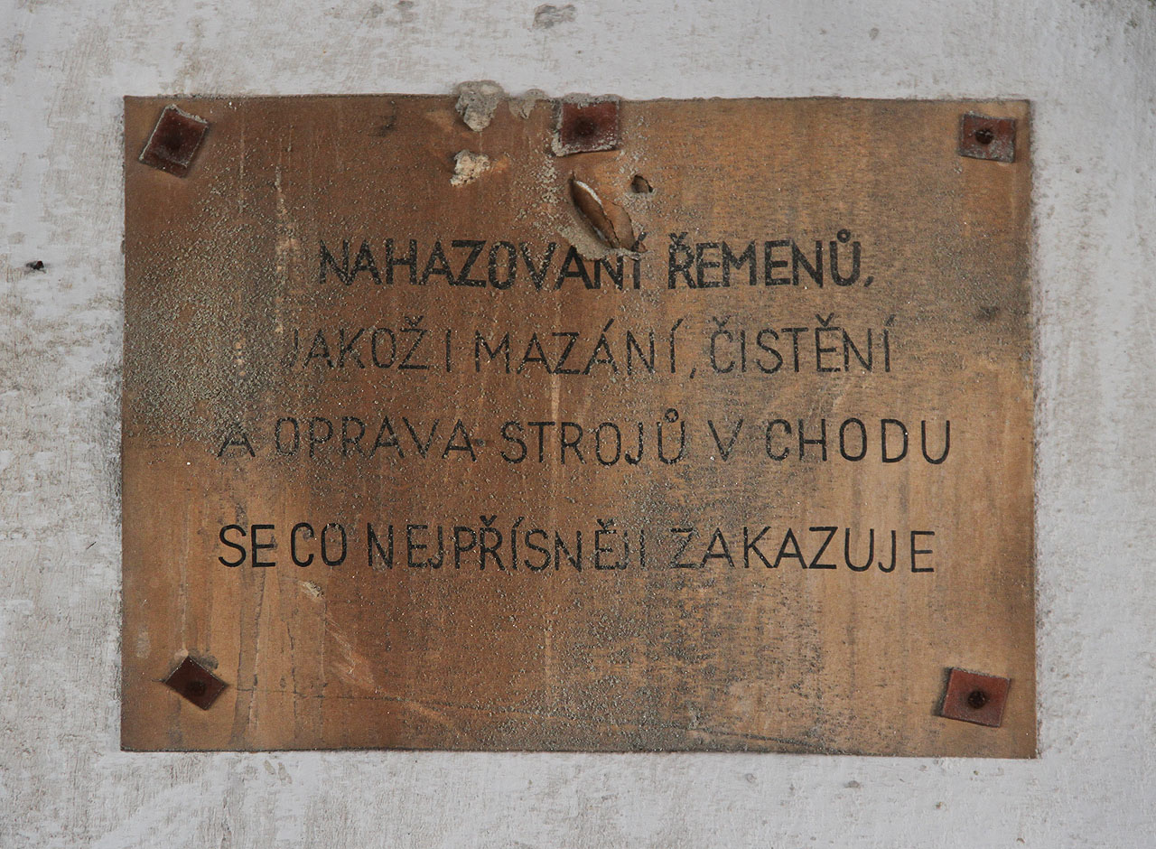 Nahazování řemenů, jakož i mazání, čištění a oprava strojů v chodu se co nejpřísněji zakazuje. Nápis, který mě děsí při vzpomínce na vyprávění o praprastrýci, kterému řemen transmise v cukrovaru utrhl ruku a on na místě vykrvácel.