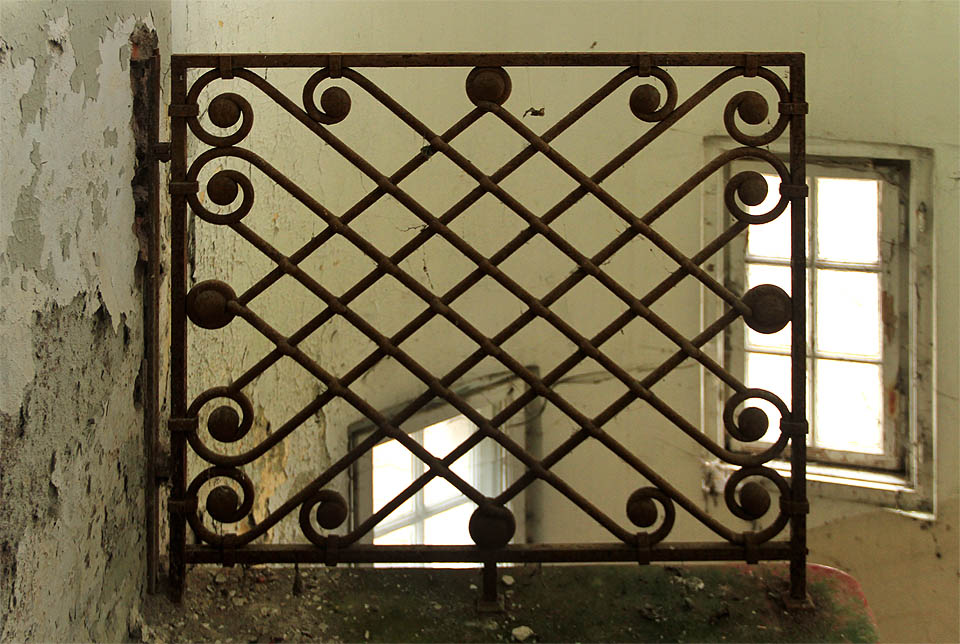 Ozdobná mříž nad schodištěm je přišroubovaná příliš pevně na to, aby ji někdo ukradl.