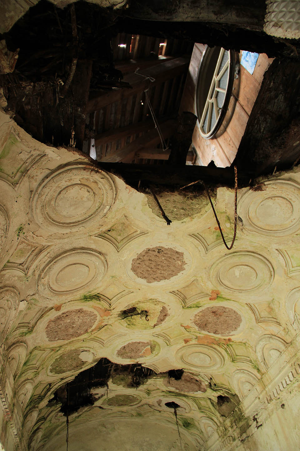 Stropem koupelny se lze dívat na půdu, kde někdo nedovřel půlkruhové okno.