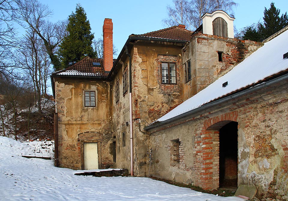 Hospodářské budovy u vstupu vypadají středně obydleně.