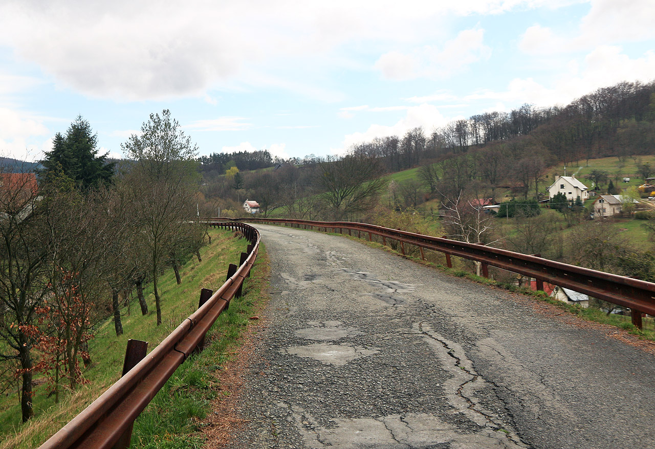 Nedostavěná dráha z Vizovic do Horní Lidče byla pojata jako moderní železnice na mohutných náspech a s tunely. Na snímku místní komunikace na tělese nedokončené trati v obci <a href="/Tema/Ublo">Ublo</a>.